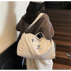 Rear view of a traveler carrying a beige travel bag with a shoulder strap on stairs