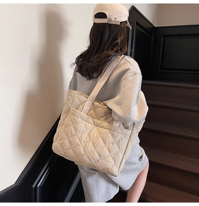 Macro detail of beige quilted padded tote bag showing diamond stitching and front pocket
