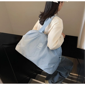 Light blue waterproof travel bag worn by model, showing spacious capacity and wide strap
