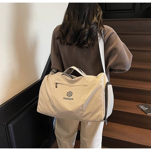 Close-up of beige travel bag with detachable shoulder strap on indoor wooden stairs