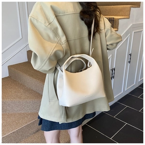 Detail view of cream bucket bag with pebbled leather texture and adjustable strap