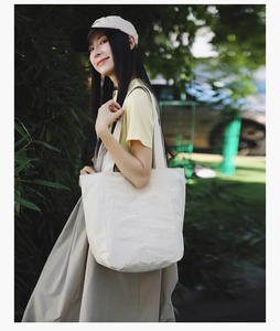 Close-up of beige large capacity canvas tote bag with textured finish and wide strap