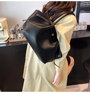 Close-up of black lychee grain leather texture and adjustable metal buckle on tote bag