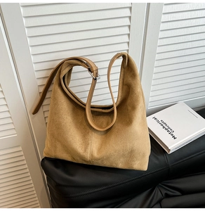 Detailed view of brown suede shoulder bag with adjustable silver buckle in minimalist setting