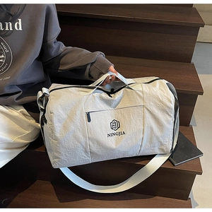 Close-up of light grey waterproof travel bag with brand logo and adjustable shoulder strap