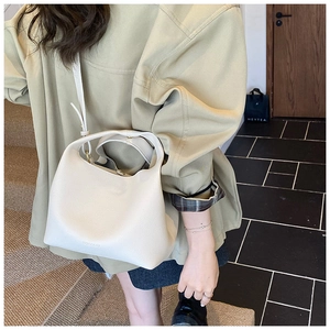 Detail of white litchi pattern leather bucket bag with top handle and adjustable strap