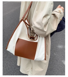 Detailed shot of large contrast canvas tote bag with brown leather pocket and strap
