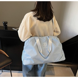 Lifestyle shot showing the back view of a light blue large capacity nylon travel bag on model