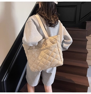 Close-up of beige quilted tote bag with classic diamond stitch pattern and side brand label