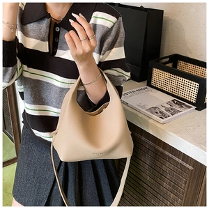 Detail of light beige bucket bag showing litchi texture and minimalist brand logo