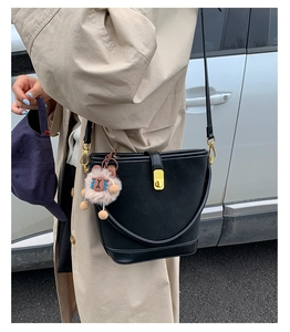 Borsa a secchiello in pelle nera opaca con chiusura dorata e ciondolo in peluche