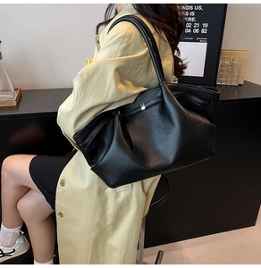 Close-up of black lychee leather handbag texture with pleated design and gold buckle
