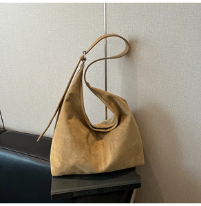 Detail of suede hobo bag in ginger yellow on books with silver metal buckle and strap