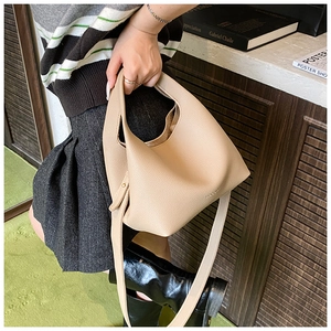 Detail of beige pebble leather bucket bag with wide shoulder strap and side buckle