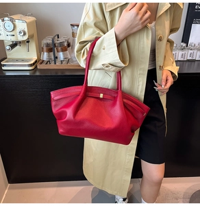 Detail of red pebbled leather shoulder bag with gold buckle and elegant pleated texture