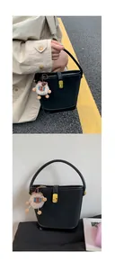 Dettaglio di una borsa a secchiello nera opaca con chiusura dorata e ciondolo a orsetto