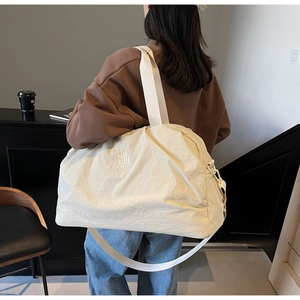 Close-up of cream travel bag with NING JIA embroidery and breathable side mesh pocket