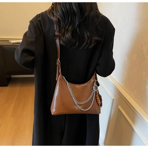 Brown faux leather shoulder bag with silver chain and wooden bead charm on a model