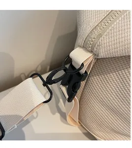 Detail of durable black metal hooks and plastic buckles on a beige travel bag strap