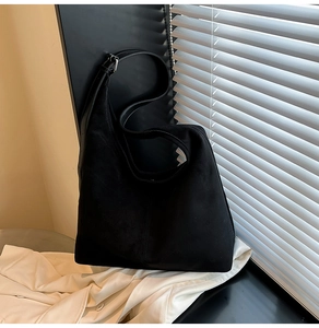 Macro view of black faux suede tote bag showing soft texture and wide shoulder strap
