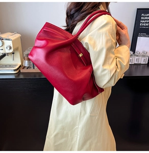 Detail of red pebbled leather tote bag with elegant pleats and golden metal buckle