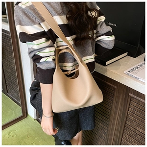 Close-up of khaki litchi grain leather hobo shoulder bag worn by model in a casual setting