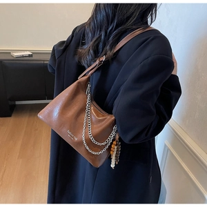 Detail of dark brown faux leather hobo bag with silver chains and wooden bead charm