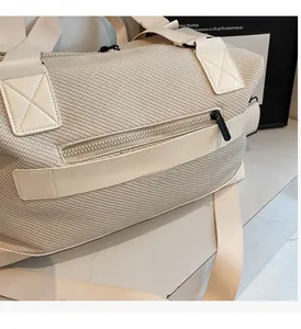 Close-up of smooth zipper detail and woven texture on beige travel duffel bag