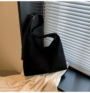 Close-up of black suede hobo tote bag featuring adjustable strap with silver metal buckle