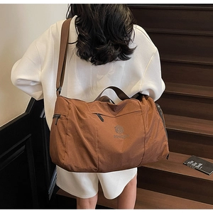 Brown nylon travel bag with wet-dry separation and adjustable shoulder strap shown on model