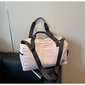 Detail of light pink waterproof travel bag with brand logo on a black sofa