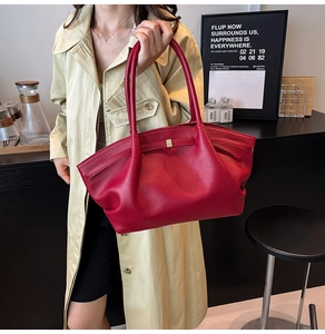 Close-up of a red lychee pattern leather tote bag with elegant gold metal buckle detail