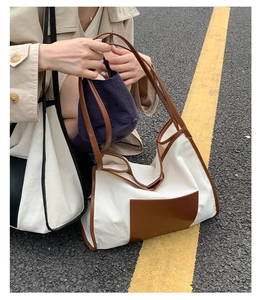 Detail of the cream canvas tote bag with brown leather trim and outdoor street view