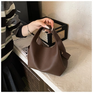 Detailed view of dark brown bucket bag featuring pebbled leather texture and integrated handle