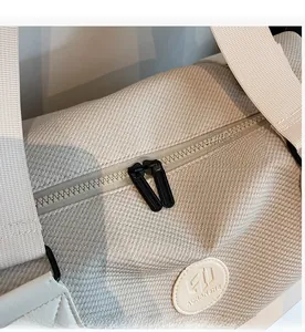 Detailed macro view of the waffle-textured fabric and smooth black zipper on the beige bag