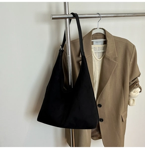 Detail of a black suede hobo bag with long shoulder strap for autumn fashion outfits