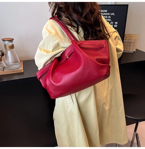 Detail of dark red lychee leather tote bag with elegant pleats and gold buckle accent
