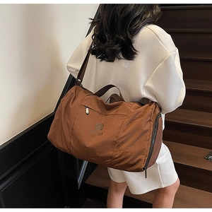 Brown travel bag shown on a model on stairs highlighting the large capacity and nylon texture