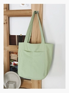 Detail view of large light green canvas tote bag with functional front pockets