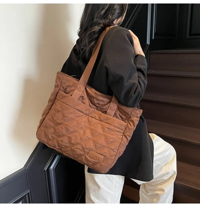 Brown quilted tote bag with classic diamond stitching and brand tag on a model