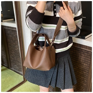 Detail of a brown lychee pattern leather bucket bag with an adjustable crossbody strap