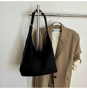 Close-up of black suede tote bag featuring leather shoulder strap and silver buckle detail