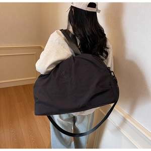 Detailed back view of a large black travel bag with shoulder strap and waterproof texture