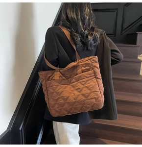 Close-up of caramel brown quilted tote bag with diamond pattern and branded leather patch
