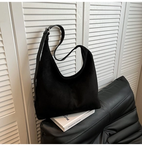 Detailed close-up of large black suede hobo bag with adjustable wide leather shoulder strap