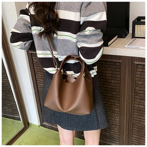 Detailed close-up of dark brown lychee grain leather bucket bag with brand embossing