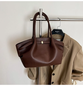 Detail view of dark brown leather tote bag with pleated texture and gold metal lock