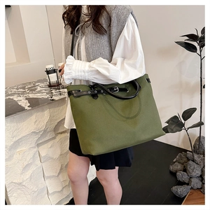 Detail of army green canvas tote bag with black leather straps and metal buckle detail