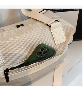 Detail view of cream travel bag with waffle texture, side zip pocket, and phone storage