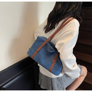 Dettaglio borsa da viaggio in denim blu con cinturini in pelle marrone sulle scale